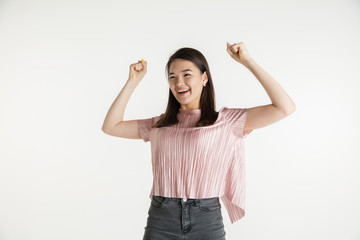 Beautiful female half-length portrait isolated on white studio background. Young emotional woman in casual clothes. Human emotions, facial expression concept. Celebrating like winner, looks happy.