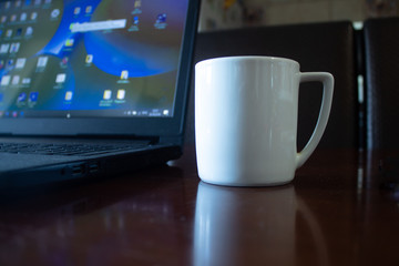 A cup of coffee on the table next to the laptop