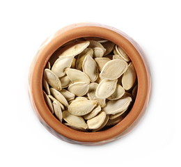Salted pumpkin seeds in clay pot, bowl isolated on white background, top view