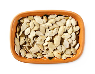 Salted pumpkin seeds in clay pot, bowl isolated on white background, top view