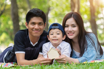 Happy young asian family having fun outside with lying and holding home together picnic in the park.