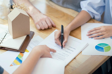 Close up, woman putting signature on document loan contract, real estate purchase, hands of woman sale represent point document to sign, contract deals success business.