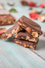 Milk chocolate bar pieces with almonds on wooden table.