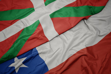 waving colorful flag of chile and national flag of basque country.
