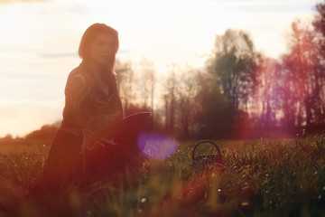 A girl in a hat on a walk in the park. A girl with a basket walks in autumn. A girl is walking along the road at sunset.