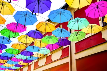 Fototapeta na wymiar Umbrellas in the air . bright small streets of the city . Overcast weather . Rainy weather