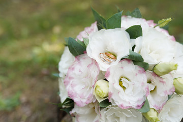 Gold wedding rings on a bouquet of white roses