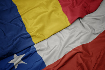 waving colorful flag of chile and national flag of romania.