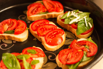 making sandwiches with tomato and basil on a baking sheet for the oven