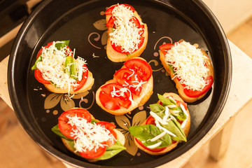 making sandwiches with tomato and basil on a baking sheet for the oven