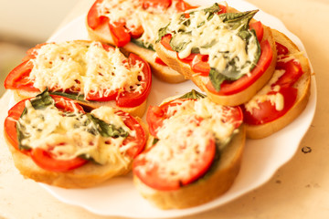 making sandwiches with tomato and basil on a baking sheet for the oven