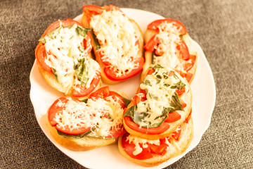 making sandwiches with tomato and basil on a baking sheet for the oven
