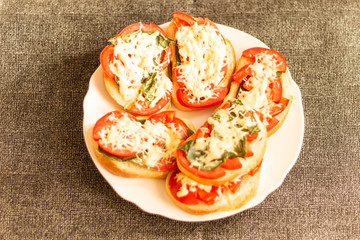 making sandwiches with tomato and basil on a baking sheet for the oven