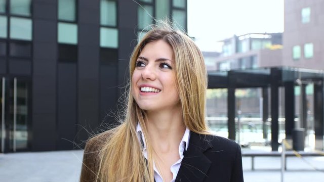 Confident young female manager walking outdoor in a modern urban setting