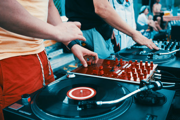 Outdoor party. Two Djs spinning vinyl record and turning mixer's controllers