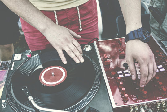 Outdoor party. Dj spinning vinyl record and turning mixer's controllers