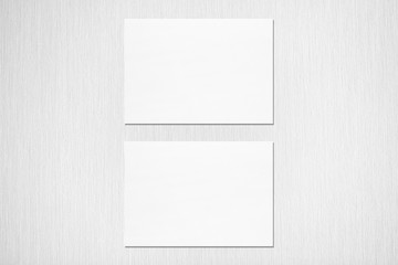 Two empty white horizontal rectangle a5 sized card mockups with soft shadows on neutral light grey concrete wall background. Flat lay, top view