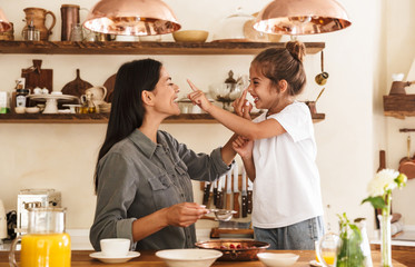 Image of funny family woman and her little daughter cooking together meal with raspberry at cozy...