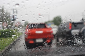 Water droplets on the windshield are on the road while heavy rain shoots blur images