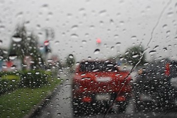 Water droplets on the windshield are on the road while heavy rain shoots blur images