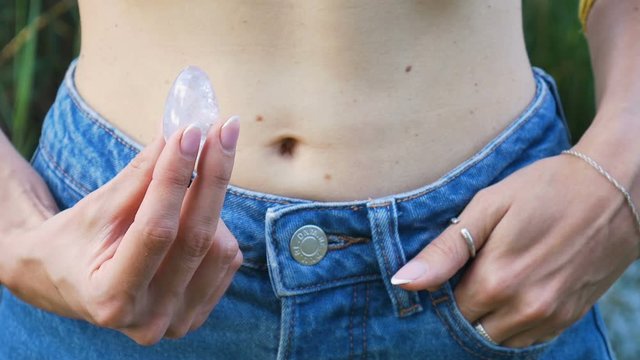 Close-up of unrecognizable woman gets out of the pocket of his jeans Yoni egg amethyst. Body care concept