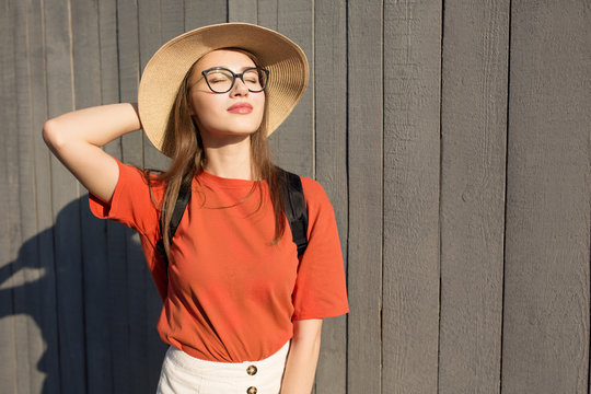 Fashion portrait of a pretty smiling woman in glasses with smartphone. Against a wooden wall