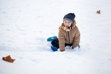 Fototapeta na wymiar Boy having fun, playing outside, surrounded with snow. Wintertime