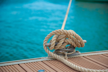 Mooring yacht rope with a knotted end tied around a cleat on a wooden pier