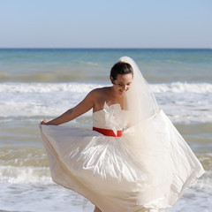 Fototapeta na wymiar Pretty young bride walking on a beach