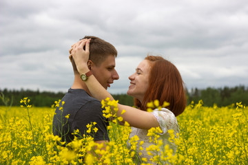 Naklejka na ściany i meble Beautiful couple in a yellow rapeseed field