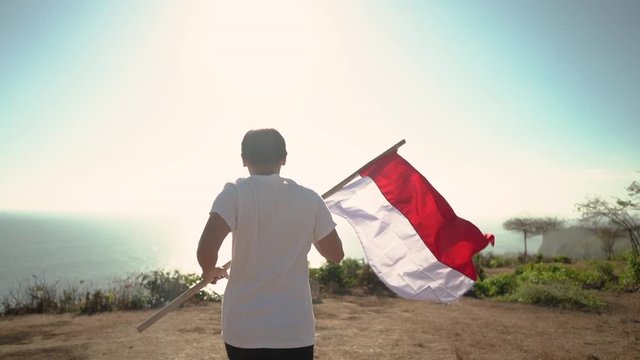 asian man with indonesian flag of indonesia on top of the mountain
