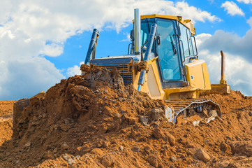 Obraz premium Crawler bulldozer - excavator with clipping path on a background with blue sky and clouds. work on construction site or sand pit