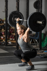 Fototapeta na wymiar Strong female weight lifter doing snatch with heavy barbell in gym.
