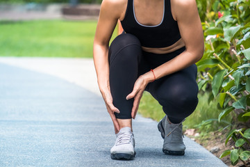 Asian woman holding her ankle after a twist injury during running