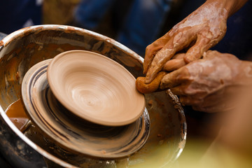 The hands of a potter, creating an earthen jar on the circle, close-ups