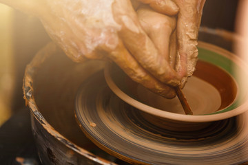 The hands of a potter, creating an earthen jar on the circle, close-ups