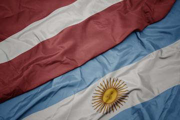 waving colorful flag of argentina and national flag of latvia.