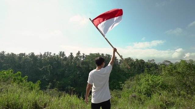 asian man with indonesian flag of indonesia on top of the mountain
