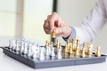 A young business man is playing chess, business strategy to be successful