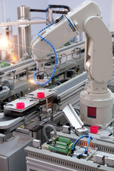 Focus on robotic arm's gripper. Industry 4.0 concept; artificial intelligence in smart factory. Robot picks up the product from automated car on the manufacturing line. Selective focus.