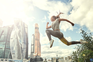 Fototapeta na wymiar Young woman with fit body jumping and running. Female model in sportswear exercising outdoors.