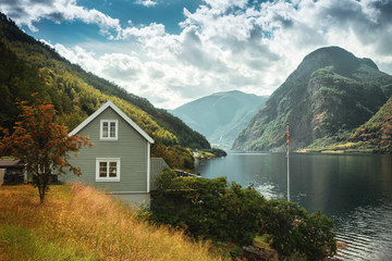 Typical Norwegian  house in the background of a picturesque fjord. Beautiful Norwegian landscape with a house and atmospheric sky.