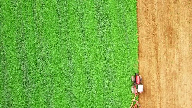Tractor with plough working on a field. Farmer use green manure for organic growing.  Agriculture from above. Environmentally friendly farming.