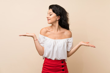 Young woman over isolated background holding copyspace with two hands