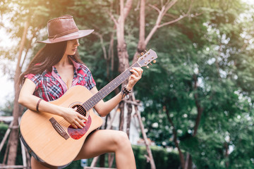 Portrait of caucasian young woman in checkered shirt and cowboy hat. She is playing country music...