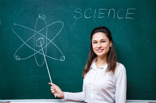 young teacher talks about science near blackboard