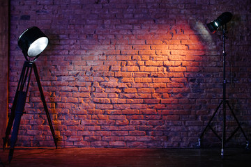 Old retro red brick wall being lit by a stage light bulb light. Constant light modifier projecting light on it - obrazy, fototapety, plakaty