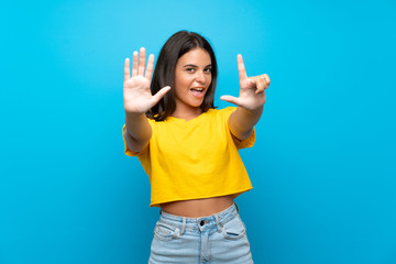 Young girl over isolated blue background counting seven with fingers