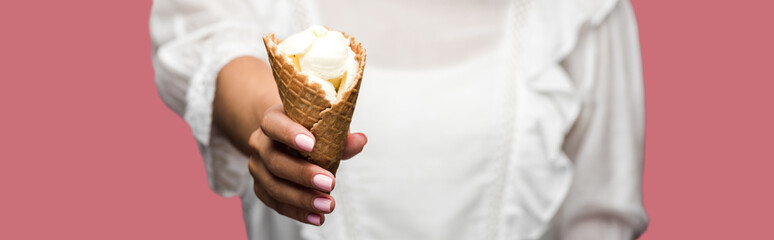 panoramic shot of woman in dress holding tasty ice cream cone isolated on pink