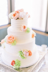 Obraz na płótnie Canvas Fine white wedding cake decorated with pink and orange peony flowers, copy space